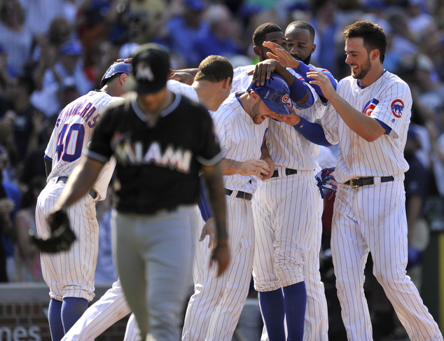 Chicago Cubs Matt Szczur is mobbed by teammates after scoring the winning run on a wild pitch by Miami Marlins A.J. Ramos during the ninth inning of a base