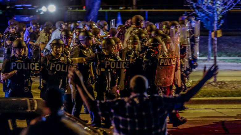 Police move in on a group of protesters throwing rocks at them in Milwaukee Sunday Aug. 14 2016. Police said one person was shot at a Milwaukee protest on Sunday evening and officers used an armored vehicle to retrieve the injured victim during a secon