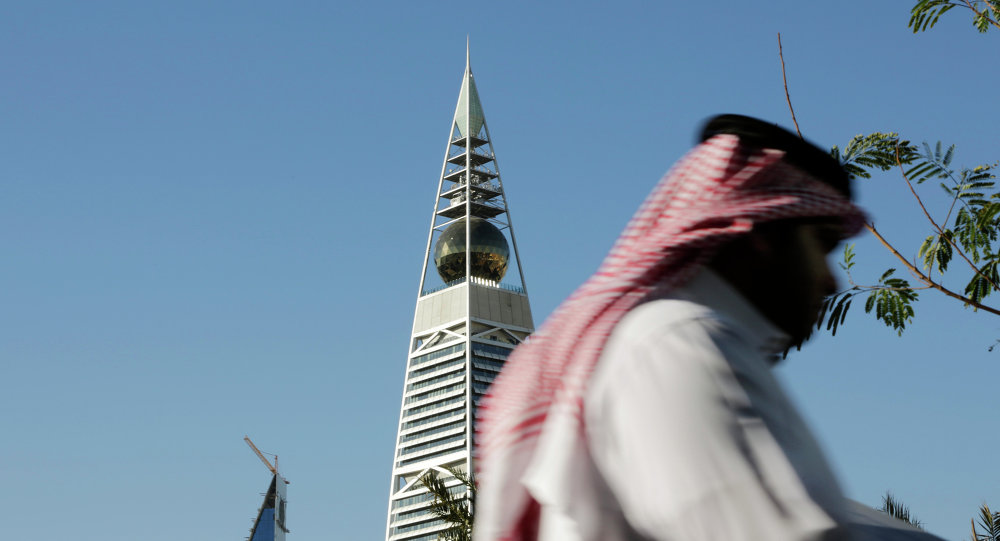 A Saudi man passes the al Faisaliya tower in Riyadh Saudi Arabia