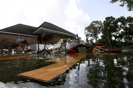 Debris is seen floating in flood water in front of a damaged home in St. Amant Louisiana U.S