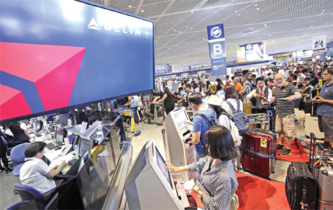 TOKYO Passengers check in at the Delta Air Lines counter at Narita international airport in Narita east of Tokyo yesterday. More than 1,000 people spent the night at the Narita airport because of a computer shutdown that halted Delta Air Lines flights