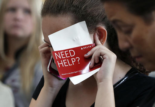 Konstance Woods talks on her cell phone with an agent as she stands in line at the Delta ticketing counter at Washington's Ronald Reagan Washington National Airport as her family tries to get to Ralei