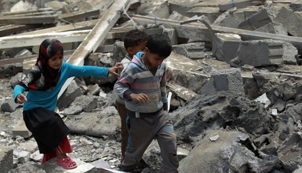 Yemeni children walk amidst the rubble of a house in Yemen's Houthi rebel-held capital Sanaa