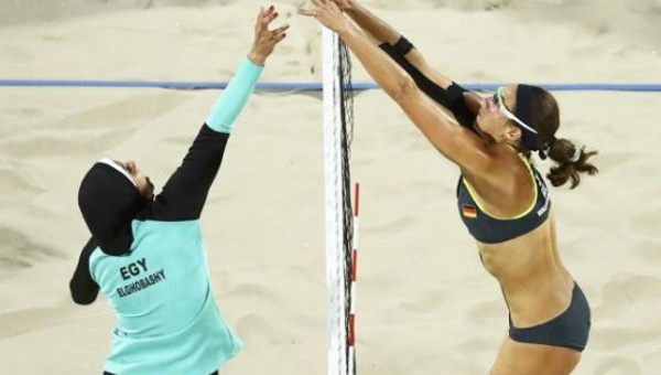 Doaa Elghobashy of Egypt and Kira Walkenhorst of Germany reach for the ball during a beach volleyball match at Rio Olympics