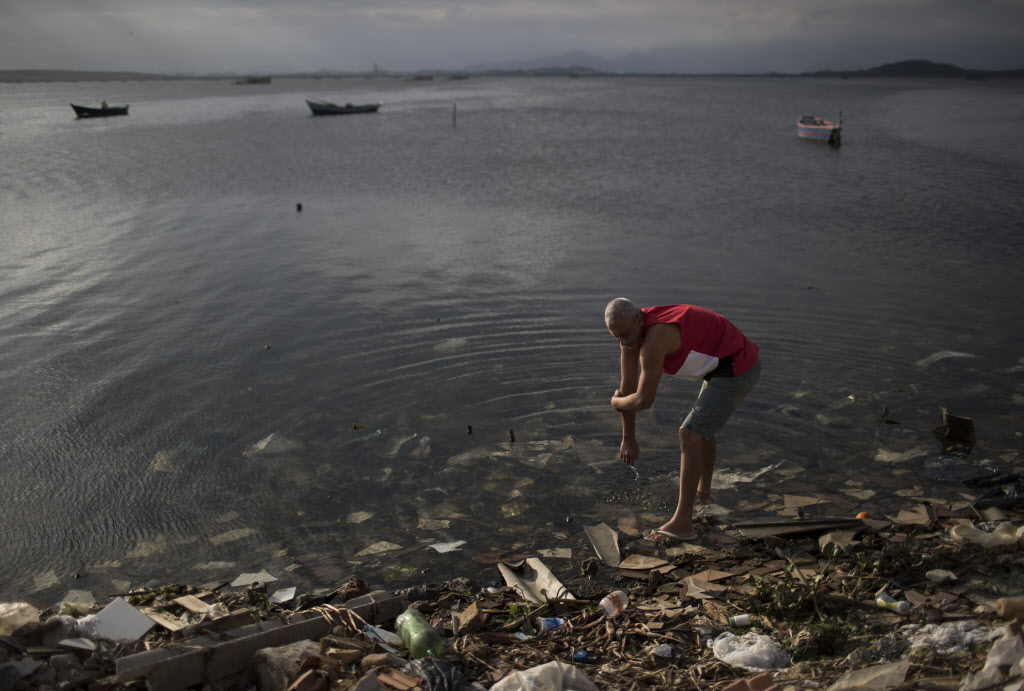 A man washes himself in the polluted waters of Guanabara Bay in Rio de Janeiro Brazil on Saturday. While local authorities including Rio Mayor Eduardo Paes have acknowledged the failure of the city's water cleanup efforts calling it a'lost chance