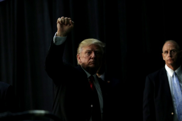 Republican presidential candidate Donald Trump gestures to supporters as he makes his way off stage following a rally