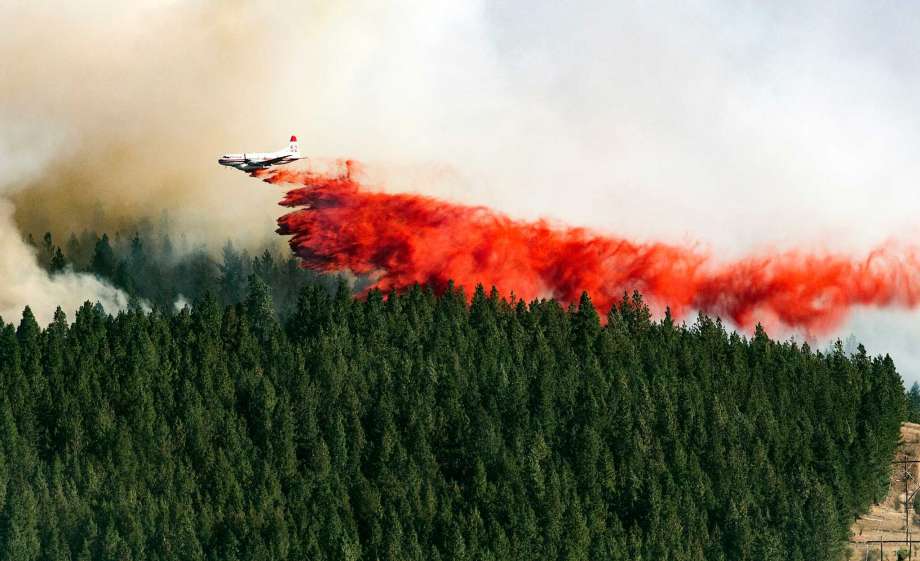 A plane drops a load of fire retardant on the north side of Beacon Hill Sunday Aug 21 2016 in Spokane Wash. The fast moving wildfire is threatening structures as it moves in a north-easterly direction. Ph