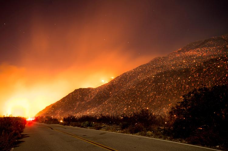 Embers from a wildfire smolder along a California road on Wednesday