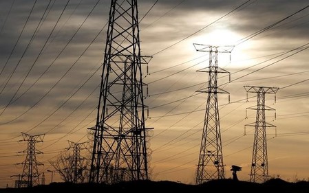 A Women carries fire wood on her head as she walks below Eskom's Elecricity pylons in Soweto,South Africa