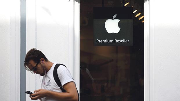 A man looks at his phone as he walks past an authorised apple reseller store in Galway Ireland