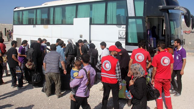 Syrian rebel fighters and their families helped by volunteers of the Red Crescent collect their bags from a coach upon their arrival in the rebel-held northwestern city of Idlib