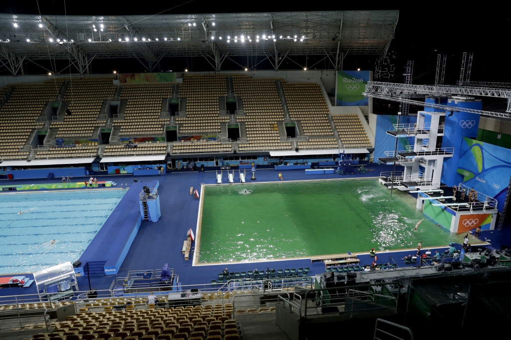 The water of the diving pool at right appears a murky green in stark contrast to the pool's previous day's color and also that of the clear blue water in the second pool for water polo at the venue as divers train in the Maria Lenk Aquatic Cent