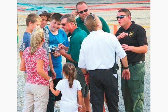 Fair officials including Fair Board President Bobby Holt center in green shirt and law enforcement talk to witnesses Monday Aug. 8 2016 after an accident on the Ferris wheel Mondayat a county fair in Greenville Tenn. Police say one of three people