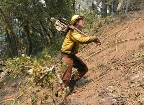 Timber faller Jeff Turpin hiked up a hillside with his chainsaw in while cutting a fire break for a wildfire in Carmel Valley Calif. on Saturday