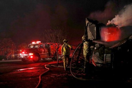 Firefighters spray water into a damaged building while battling the Clayton Fire at Lower Lake in California