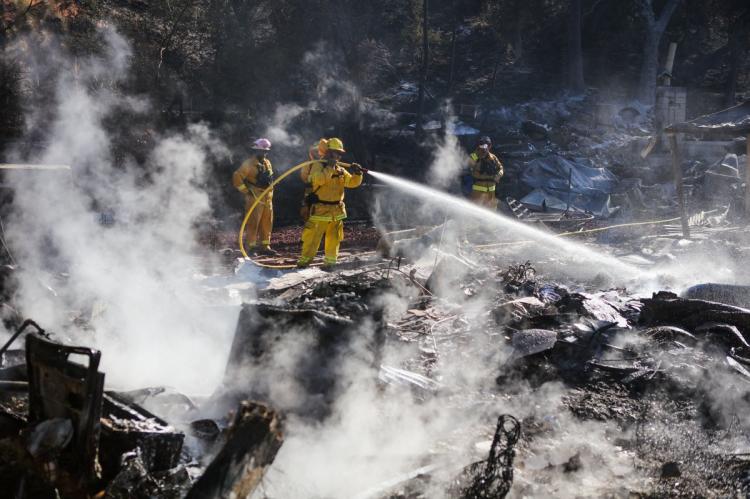 Firefighters work to contain embers on the remains of a house destroyed by the Clayton Fire in Lower Lake California August 15th 2016