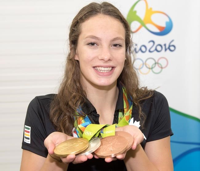 Canada's Penny Oleksiak from Toronto holds up her four medals a gold silver and two bronze she won at the 2016 Summer Olympics during a news conference Sunday