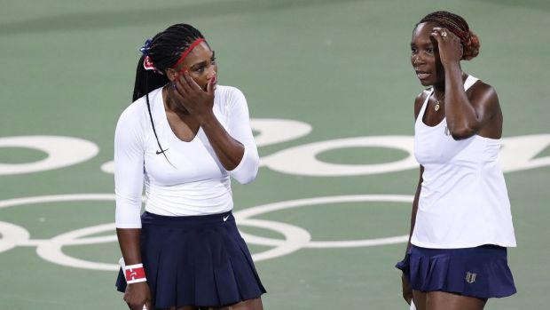 Venus Williams of the United States right talks with her sister Serena after losing a point in a doubles match