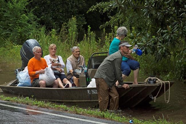 People arrive an area to be evacuated by members of the Louisiana Army National Guard near Walker La. after heavy rains inundated the region Sunday Aug. 14 2016