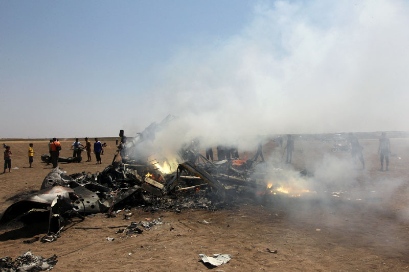 Rebel fighters and civilians inspect the wreckage of a Russian helicopter that had been shot down in the north of Syria's rebel-held Idlib province Syria on Monday