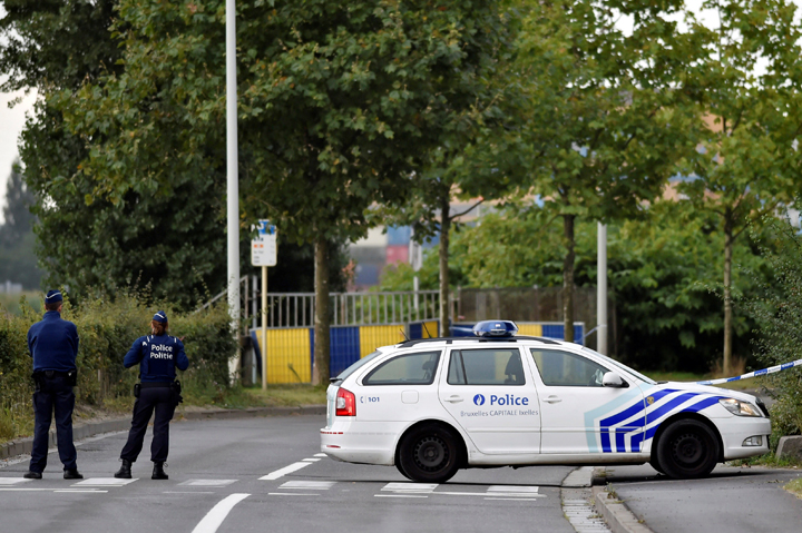 Belgian police officers secure a road near the Belgium's National Institute of Criminology after arsonists set fire to it in Brussels Belgium