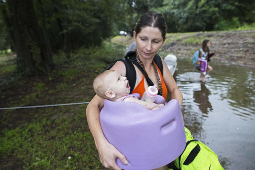 Danielle Blount carries her 3-month-old baby Ember to a truck from the Louisiana Army National Guard as they evacuate the area near Walker La. after heavy rains inundated the region Sunday Aug. 14 2016