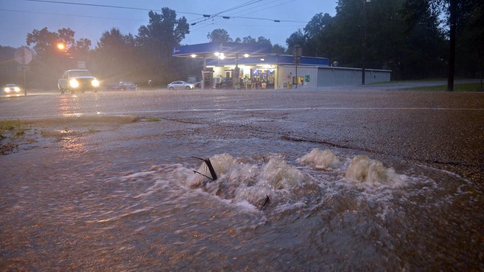 Floodwaters surge from a crack in the parking lot on the corner of highways 584 and 51 in Osyka Mississippi early Friday Aug. 12 2016