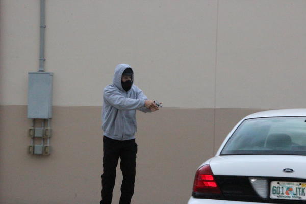 Sue Paquin captured this image of Punta Gorda police officer Lee Coel as he fired a round that struck 73-year-old Mary Knowlton who was standing on the opposite side of the police car. Knowlton later died as a result of her injuries