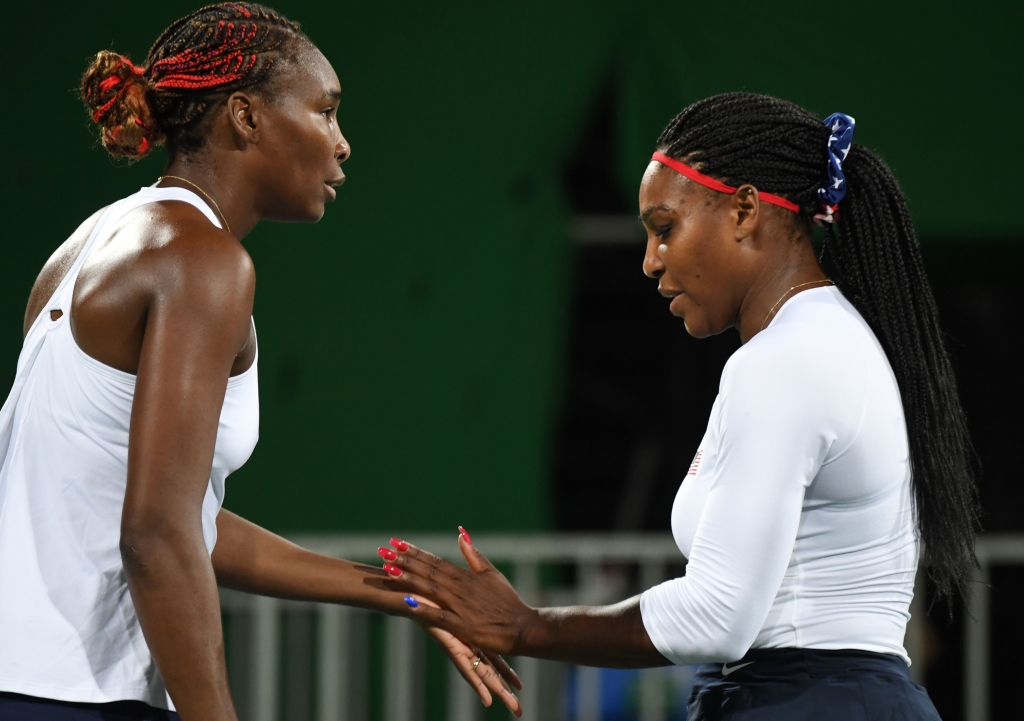 Serena Williams and Venus Williams celebrate after winning a point during their women's first-round doubles tennis match against the Czech Republic team at the Olympic Tennis Centre of the Rio de Janeiro 2016 Olympic Games in Rio de Janeiro A