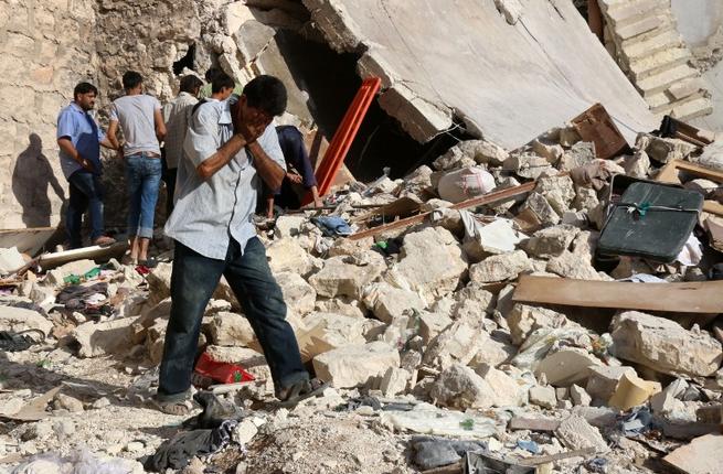 A Syrian man reacts as rescuers look for victims under the rubble of a collapsed building following a reported air strike on the rebel-held neighborhood of Sakhur in Aleppo