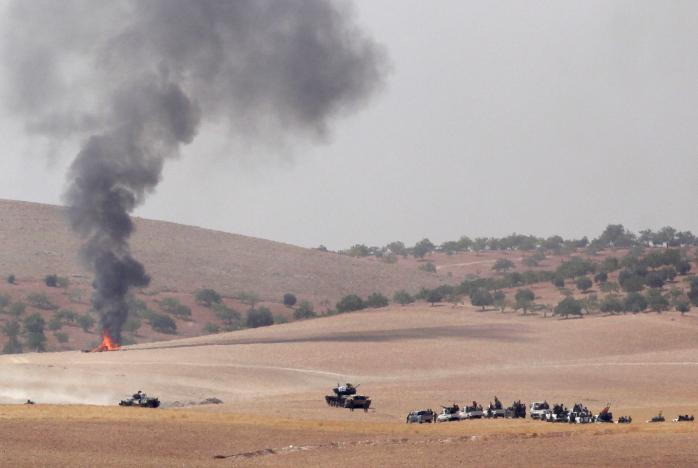 Turkish army tanks and Turkish-backed Syrian fighters make their way in the Syrian border town of Jarablus as it