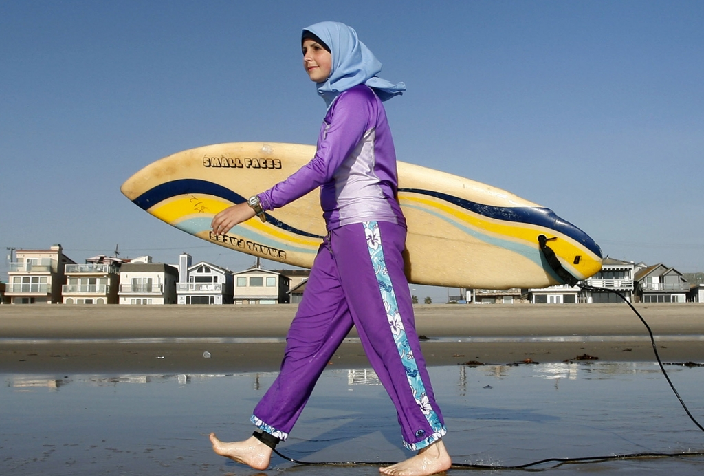 FILE ** Sama Wareh walks along the sand dressed in swimwear designed for Muslim women Newport Beach Calif. Thursday Feb. 15 2007. Muslim girls and women are increasingly participating in athletic activities especially