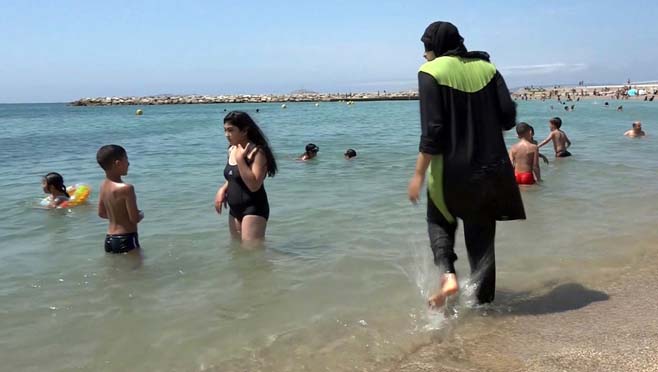 Nissrine Samali 20 gets into the sea wearing traditional Islamic dress in Marseille southern France. The French resort of Cannes has banned full-body head-covering swimsuits worn by some Muslim