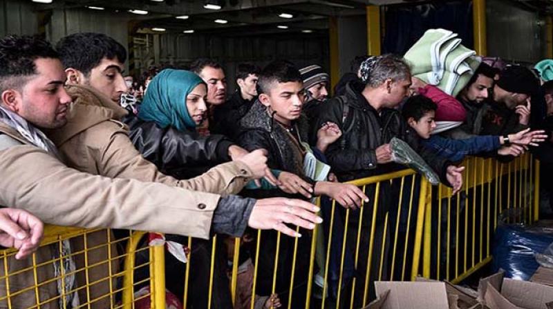 Refugees and migrants wait for free blankets and raincoats before disembarking from a government chartered ferry