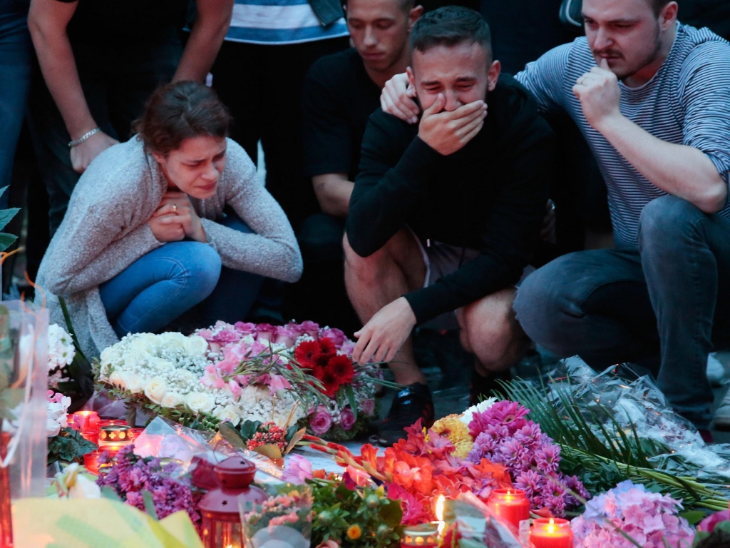 People mourn near a shopping center in Munich on July 23 the day after a shooting spree there left nine victims dead. The attack was one of several that month in Germany