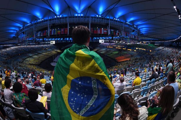 A spectator wrapped in a Brazilian flag looks on ahead the opening ceremony of the Rio 2016 Olympic Games at the Maracana stadium