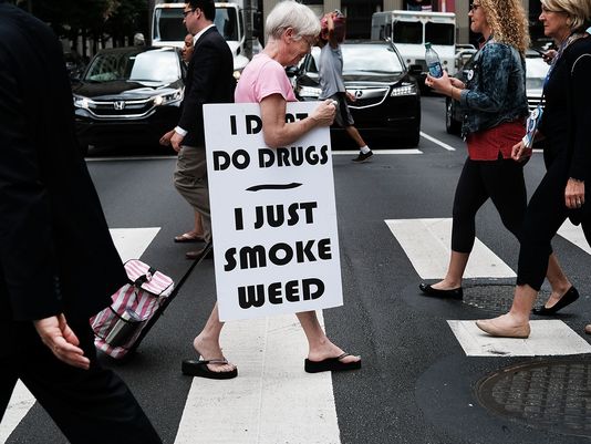 A woman walks with a sign supporting legalizing marijuana during the Democratic National Convention in Philadelphia