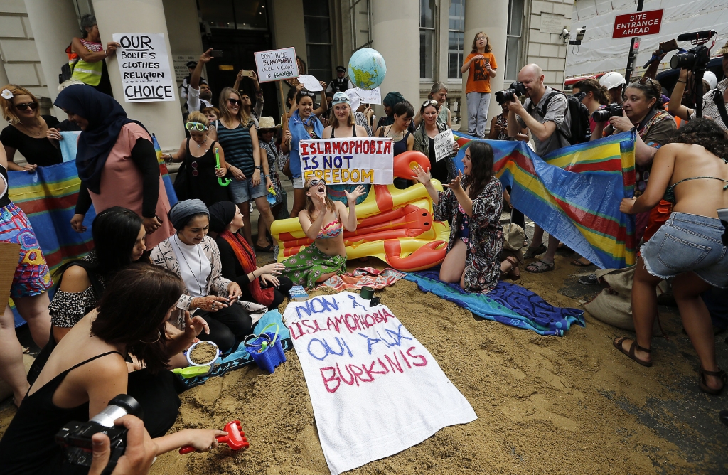 Activists protest outside the French embassy during the'wear what you want beach party in London Thursday Aug. 25 2016. The protest is against the French authorities clampdown on Muslim women wearing burkinis on the beach. Writing on the sign reads