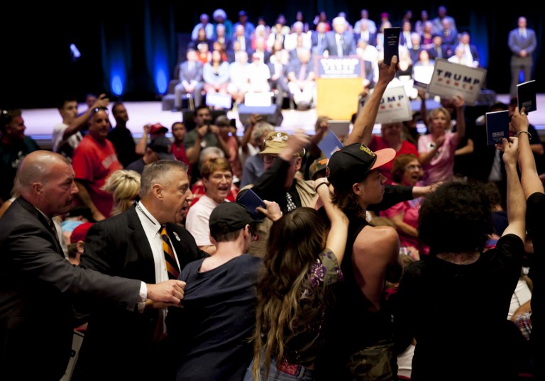 Protesters holding up copies of the Constitution are escorted out of Republican presidential candidate Donald Trump's speech at the Merrill Auditorium in Portland Maine