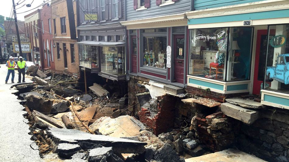 Workers gather by street damage after Saturday night's flooding in Ellicott City Maryland on Sunday