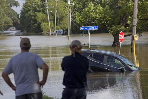 Residents survey the flood water on Old Jefferson Highway at Bayou Manchac in Prairieville La. Tuesday Aug. 16 2016. Rivers and creeks were still dangerously bloated in areas south of Baton Rouge as people filled sandbags there to protect their house