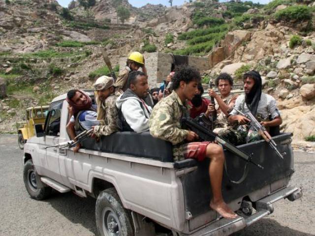 Pro-government fighters ride on the back of a patrol truck in a village taken by pro-government forces from the Iran-allied Houthi militia