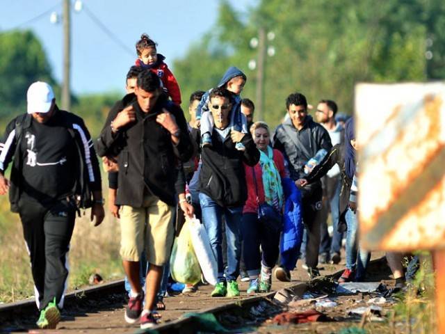 Refugees from Middle Eastern countries walk on railway tracks to the Hungarian border near the Northern Serbia's town of Horgos