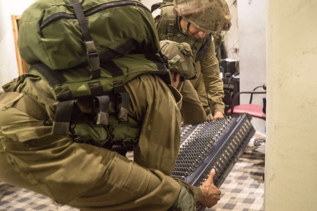 IDF soldiers remove a piece of broadcasting equipment as they shutter the al Sabanel radio station in Dura