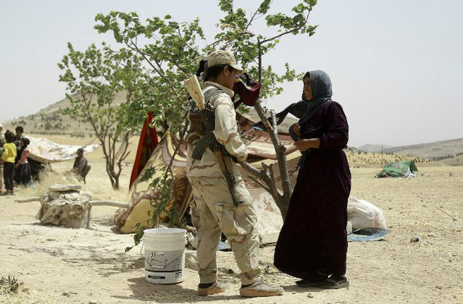 A Syrian woman who fled the assault launched by Arab and Kurdish forces against Islamic State fighters in the town of Manbij talks to a Kurdish fighter upon her arrival at an encampment on the outskirts of the town