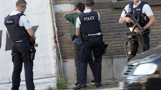 Police officers check the identification of a man near the police headquarters in Charleroi after the machete attack