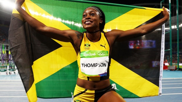 Elaine Thompson poses with the Jamican flag after winning the women's 100m Olympic title