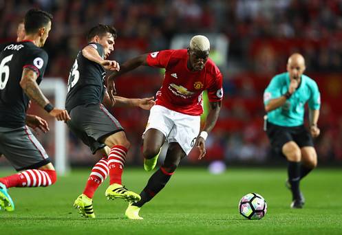 MANCHESTER ENGLAND- AUGUST 19 Paul Pogba of Manchester United skips a challenge by Pierre Emile Hojbjerg of Southampton during the Premier League match between Manchester United and Southampton at Old Trafford