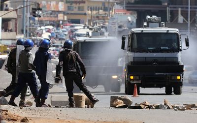 Anti-riot police clear roads during a protest by opposition youths who were demonstrating against alleged brutality by security agents in the capital Harare Zimbabwe on Wednesday