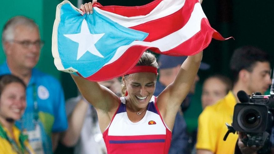 Monica Puig of Puerto Rico celebrates holding her country's flag after winning the gold medal match in the women's tennis competition at the 2016 Summer Olympics in Rio de Janeiro Brazil Saturday Aug. 13 2016